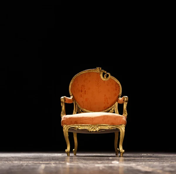 Vintage oranje stoel op het theater podium tegen donkere zwarte achtergrond — Stockfoto