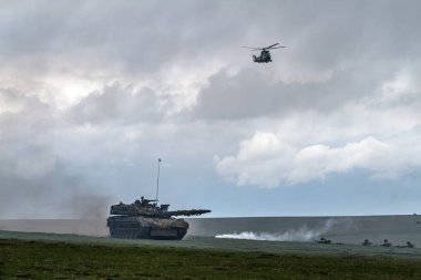 askeri helikopter uçağı gökyüzünde uçan, tank, duman ve çalışan askerler 