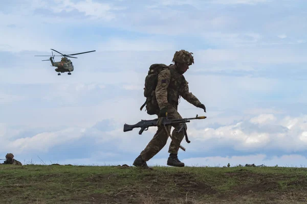 军用直升机在天空中飞行 士兵带着武器行走 — 图库照片