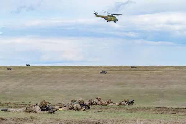 Askeri Helikopter Uçağı Gökyüzünde Uçan Silah Ile Alanda Yatan Askerler — Stok fotoğraf