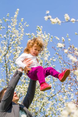 Baba küçük kız, arka planda bahar ağacı ile oynuyor 