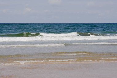 rüzgarlı yaz gününde büyük su dalgaları ve ışık mavi ve bulutlu gökyüzü kum plaj