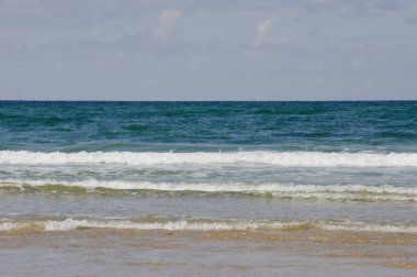 rüzgarlı yaz gününde büyük su dalgaları ve ışık mavi ve bulutlu gökyüzü kum plaj