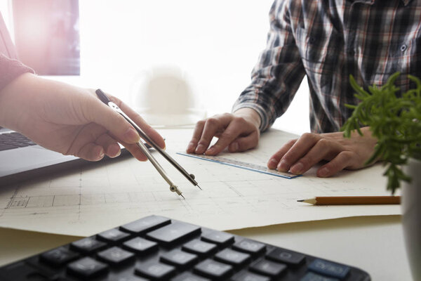 Architects working on blueprint, real estate project. Architect workplace - architectural project, blueprints, ruler, calculator, laptop and divider compass. Construction concept. Engineering tools.