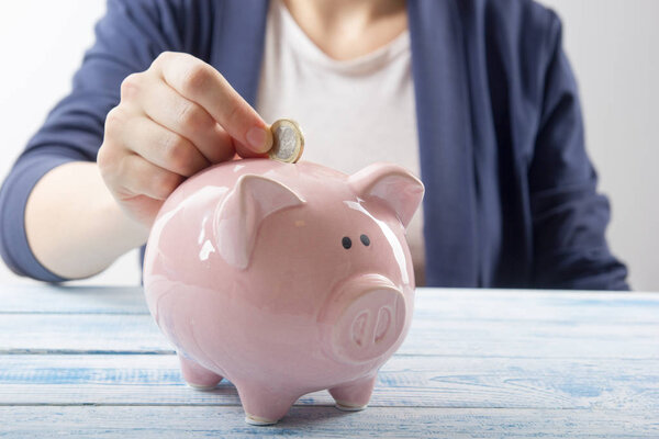 Hand putting coin into piggy bank closeup. selective focus