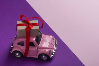 Pembe retro oyuncak araba hediye kutusu pastel arka plan üzerinde teslim. Üstten Görünüm