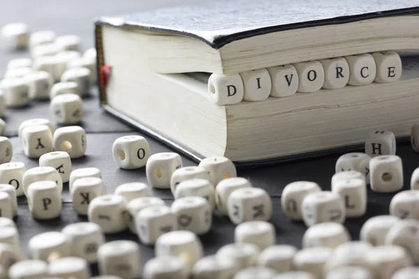 Palabra - Divorcio compuesto de letras de madera sobre la mesa con anillos de boda . —  Fotos de Stock