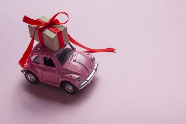 Pembe retro oyuncak araba hediye kutusu pastel arka plan üzerinde teslim. Üstten Görünüm