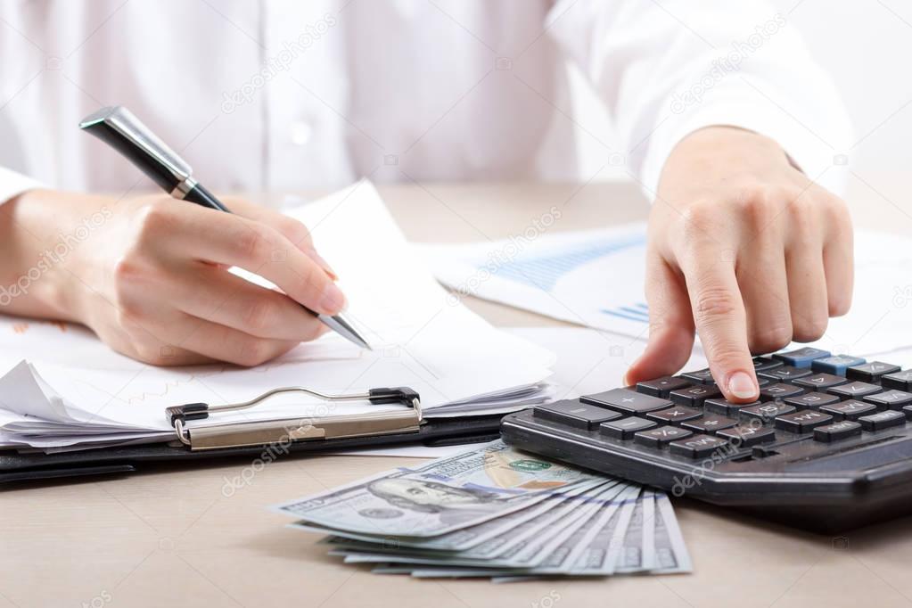 Close up of female accountant or banker making calculations. Savings, finances and economy concept