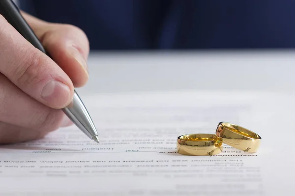 Ruce ženy, manžela, který podepisuje rozhodnutí o rozvodu, zrušení manželství, doklady o rozluce, žádosti o rozvod nebo předmanželskou dohodu vyhotovenou právníkem. Svatební prsten — Stock fotografie