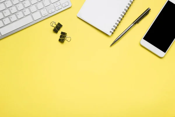 Escritório mesa amarela com laptop, smartphone e outros suprimentos de trabalho com xícara de café. Visão superior com espaço de cópia para entrada do texto. Espaço de trabalho de designer na mesa de mesa elementos essenciais em leigos planos — Fotografia de Stock