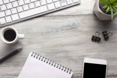 Bilgisayarlı beyaz masa ofisi, akıllı telefon ve bir fincan kahveli diğer iş malzemeleri. Metni kopyalamak için üst görünümü kullan. Desenci çalışma alanı düz masa üzerinde temel elementler yatıyordu