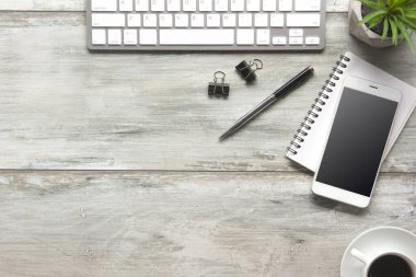 Bilgisayarlı beyaz masa ofisi, akıllı telefon ve bir fincan kahveli diğer iş malzemeleri. Metni kopyalamak için üst görünümü kullan. Desenci çalışma alanı düz masa üzerinde temel elementler yatıyordu