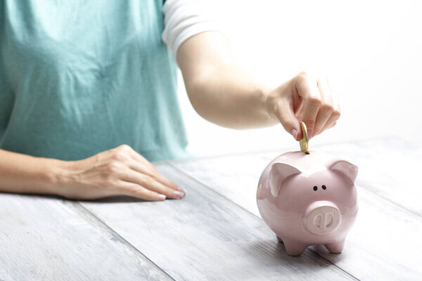woman hand putting money coin into piggy for saving money wealth and financial concept