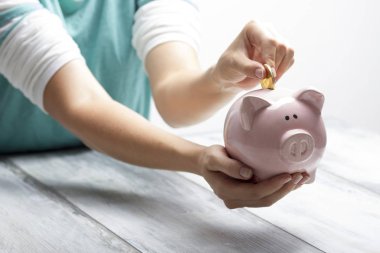 Kadın, para biriktirmek ve finansal konsept için domuzcuğa para yatırıyor.