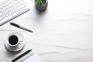 Bilgisayarlı beyaz masa ofisi, akıllı telefon ve bir fincan kahveli diğer iş malzemeleri. Metni kopyalamak için üst görünümü kullan. Desenci çalışma alanı düz masa üzerinde temel elementler yatıyordu