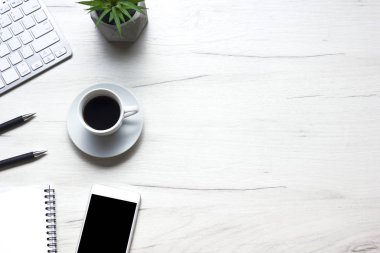 Bilgisayarlı beyaz masa ofisi, akıllı telefon ve bir fincan kahveli diğer iş malzemeleri. Metni kopyalamak için üst görünümü kullan. Desenci çalışma alanı düz masa üzerinde temel elementler yatıyordu
