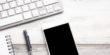 Bilgisayarlı beyaz masa ofisi, akıllı telefon ve bir fincan kahveli diğer iş malzemeleri. Metni kopyalamak için üst görünümü kullan. Desenci çalışma alanı düz masa üzerinde temel elementler yatıyordu