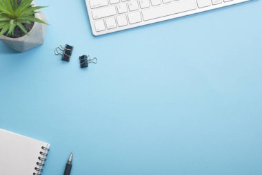 Dizüstü bilgisayarı, akıllı telefonu ve bir fincan kahveli diğer iş malzemeleri olan mavi masa ofisi. Metni kopyalamak için üst görünümü kullan. Desenci çalışma alanı düz masa üzerinde temel elementler yatıyordu