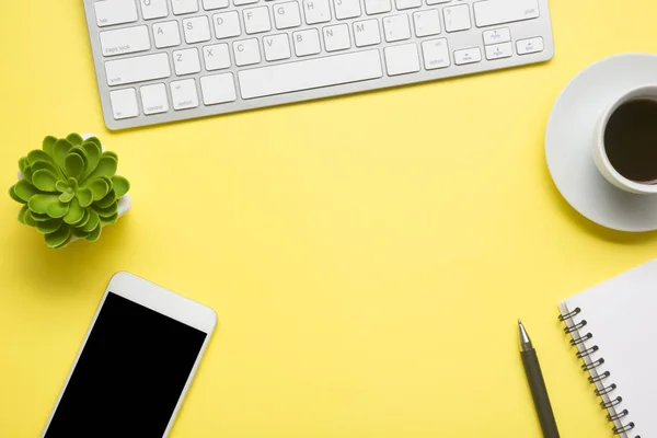 Escritório mesa amarela com laptop, smartphone e outros suprimentos de trabalho com xícara de café. Visão superior com espaço de cópia para entrada do texto. Espaço de trabalho de designer na mesa de mesa elementos essenciais em leigos planos — Fotografia de Stock