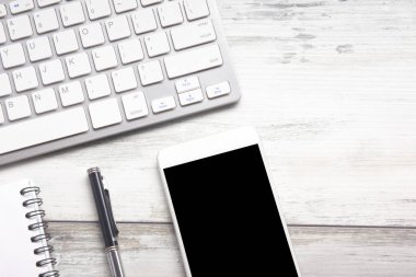 Bilgisayarlı beyaz masa ofisi, akıllı telefon ve bir fincan kahveli diğer iş malzemeleri. Metni kopyalamak için üst görünümü kullan. Desenci çalışma alanı düz masa üzerinde temel elementler yatıyordu