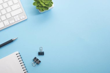 Dizüstü bilgisayarı, akıllı telefonu ve bir fincan kahveli diğer iş malzemeleri olan mavi masa ofisi. Metni kopyalamak için üst görünümü kullan. Desenci çalışma alanı düz masa üzerinde temel elementler yatıyordu