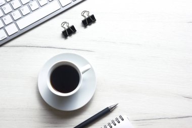 Bilgisayarlı beyaz masa ofisi, akıllı telefon ve bir fincan kahveli diğer iş malzemeleri. Metni kopyalamak için üst görünümü kullan. Desenci çalışma alanı düz masa üzerinde temel elementler yatıyordu