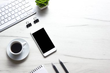 Bilgisayarlı beyaz masa ofisi, akıllı telefon ve bir fincan kahveli diğer iş malzemeleri. Metni kopyalamak için üst görünümü kullan. Desenci çalışma alanı düz masa üzerinde temel elementler yatıyordu