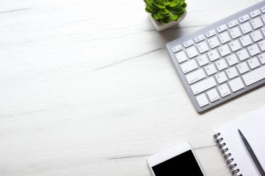 Bilgisayarlı beyaz masa ofisi, akıllı telefon ve bir fincan kahveli diğer iş malzemeleri. Metni kopyalamak için üst görünümü kullan. Desenci çalışma alanı düz masa üzerinde temel elementler yatıyordu