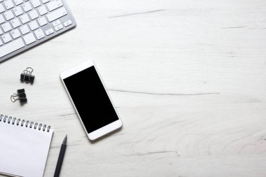 Bilgisayarlı beyaz masa ofisi, akıllı telefon ve bir fincan kahveli diğer iş malzemeleri. Metni kopyalamak için üst görünümü kullan. Desenci çalışma alanı düz masa üzerinde temel elementler yatıyordu
