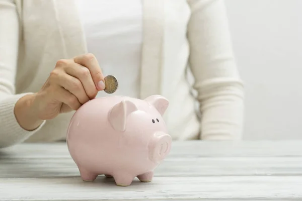 Mão mulher colocando dinheiro moeda em porquinho para economizar dinheiro riqueza e conceito financeiro — Fotografia de Stock