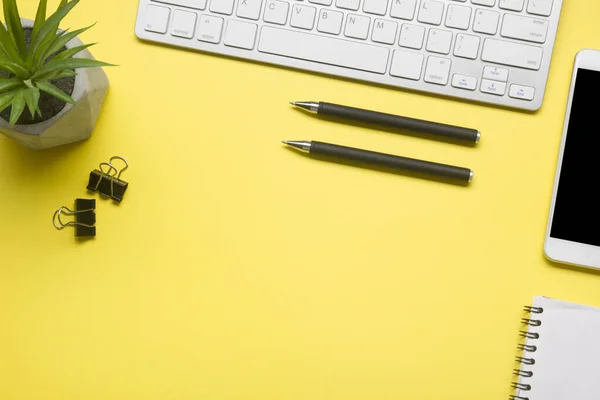 Yellow desk office with laptop, smartphone and other work supplies with cup of coffee. Top view with copy space for input the text. Designer workspace on desk table essential elements on flat lay