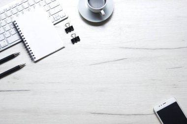 Bilgisayarlı beyaz masa ofisi, akıllı telefon ve bir fincan kahveli diğer iş malzemeleri. Metni kopyalamak için üst görünümü kullan. Desenci çalışma alanı düz masa üzerinde temel elementler yatıyordu