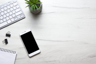 Bilgisayarlı beyaz masa ofisi, akıllı telefon ve bir fincan kahveli diğer iş malzemeleri. Metni kopyalamak için üst görünümü kullan. Desenci çalışma alanı düz masa üzerinde temel elementler yatıyordu