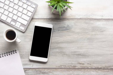 Bilgisayarlı beyaz masa ofisi, akıllı telefon ve bir fincan kahveli diğer iş malzemeleri. Metni kopyalamak için üst görünümü kullan. Desenci çalışma alanı düz masa üzerinde temel elementler yatıyordu