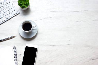 Bilgisayarlı beyaz masa ofisi, akıllı telefon ve bir fincan kahveli diğer iş malzemeleri. Metni kopyalamak için üst görünümü kullan. Desenci çalışma alanı düz masa üzerinde temel elementler yatıyordu