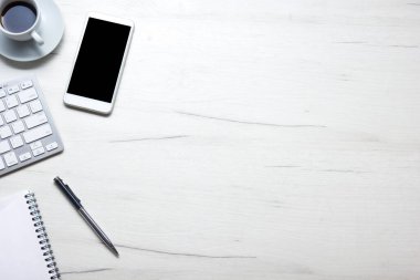 Bilgisayarlı beyaz masa ofisi, akıllı telefon ve bir fincan kahveli diğer iş malzemeleri. Metni kopyalamak için üst görünümü kullan. Desenci çalışma alanı düz masa üzerinde temel elementler yatıyordu