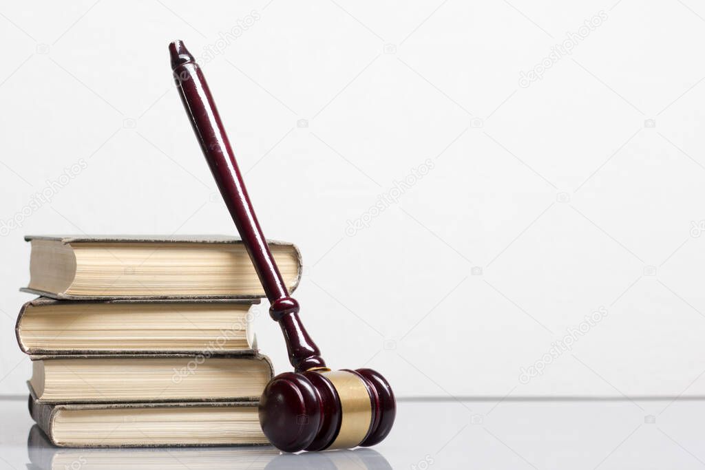 Law concept - Open law book with a wooden judges gavel on table in a courtroom or law enforcement office isolated on white background. Copy space for text