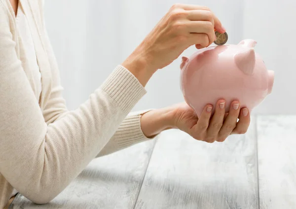 Mão mulher colocando dinheiro moeda em porquinho para economizar dinheiro riqueza e conceito financeiro — Fotografia de Stock