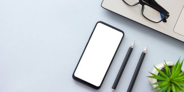 Dizüstü bilgisayarı, akıllı telefonu ve bir fincan kahveli diğer iş malzemeleri olan mavi masa ofisi. Metni kopyalamak için üst görünümü kullan. Desenci çalışma alanı düz masa üzerinde temel elementler yatıyordu