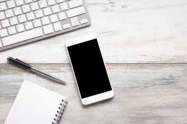 Bilgisayarlı beyaz masa ofisi, akıllı telefon ve bir fincan kahveli diğer iş malzemeleri. Metni kopyalamak için üst görünümü kullan. Desenci çalışma alanı düz masa üzerinde temel elementler yatıyordu