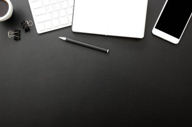 Laptop, akıllı telefon ve bir fincan kahveli diğer iş malzemeleri olan siyah masa ofisi. Metni kopyalamak için üst görünümü kullan. Desenci çalışma alanı düz masa üzerinde temel elementler yatıyordu
