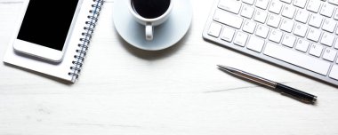 Bilgisayarlı beyaz masa ofisi, akıllı telefon ve bir fincan kahveli diğer iş malzemeleri. Metni kopyalamak için üst görünümü kullan. Desenci çalışma alanı düz masa üzerinde temel elementler yatıyordu