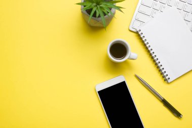 Bilgisayarlı beyaz masa ofisi, akıllı telefon ve bir fincan kahveli diğer iş malzemeleri. Metni kopyalamak için üst görünümü kullan. Desenci çalışma alanı düz masa üzerinde temel elementler yatıyordu