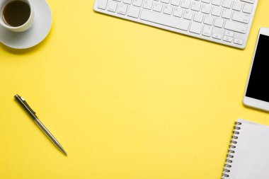 Bilgisayarlı beyaz masa ofisi, akıllı telefon ve bir fincan kahveli diğer iş malzemeleri. Metni kopyalamak için üst görünümü kullan. Desenci çalışma alanı düz masa üzerinde temel elementler yatıyordu