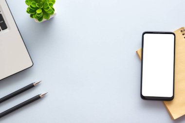 Dizüstü bilgisayarı, akıllı telefonu ve bir fincan kahveli diğer iş malzemeleri olan mavi masa ofisi. Metni kopyalamak için üst görünümü kullan. Desenci çalışma alanı düz masa üzerinde temel elementler yatıyordu