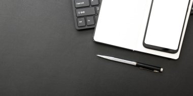 Laptop, akıllı telefon ve bir fincan kahveli diğer iş malzemeleri olan siyah masa ofisi. Metni kopyalamak için üst görünümü kullan. Desenci çalışma alanı düz masa üzerinde temel elementler yatıyordu