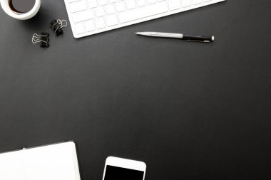 Laptop, akıllı telefon ve bir fincan kahveli diğer iş malzemeleri olan siyah masa ofisi. Metni kopyalamak için üst görünümü kullan. Desenci çalışma alanı düz masa üzerinde temel elementler yatıyordu