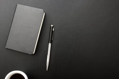 Laptop, akıllı telefon ve bir fincan kahveli diğer iş malzemeleri olan siyah masa ofisi. Metni kopyalamak için üst görünümü kullan. Desenci çalışma alanı düz masa üzerinde temel elementler yatıyordu