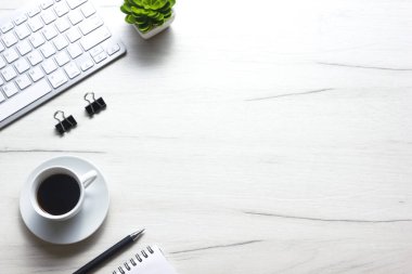 Bilgisayarlı beyaz masa ofisi, akıllı telefon ve bir fincan kahveli diğer iş malzemeleri. Metni kopyalamak için üst görünümü kullan. Desenci çalışma alanı düz masa üzerinde temel elementler yatıyordu